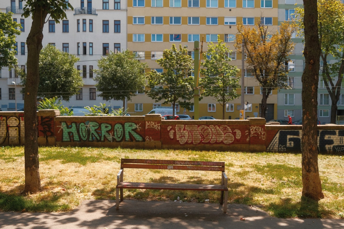Stadtszene Wien: Bank zwischen Bäumen vor Mauer